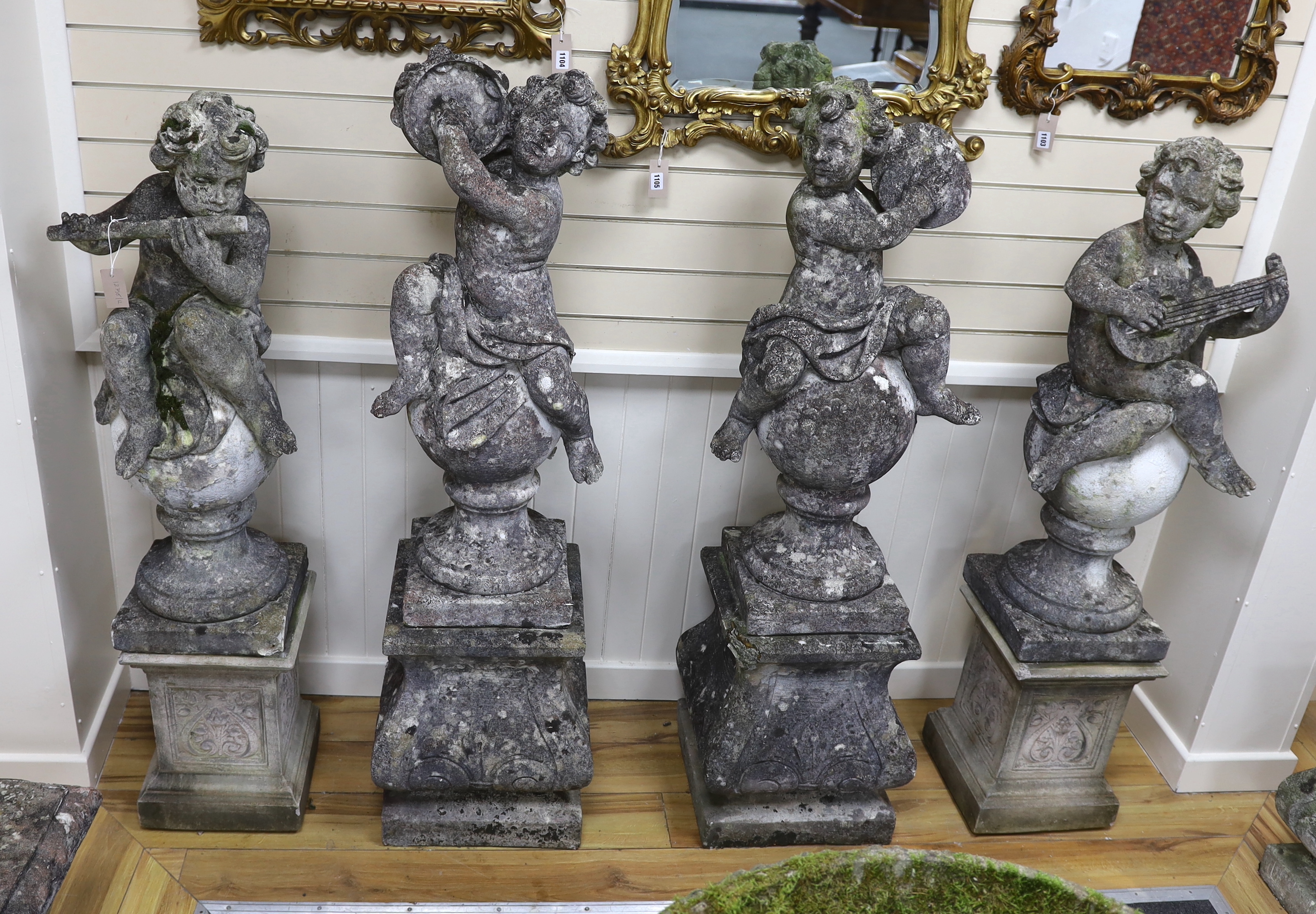 A set of four reconstituted stone garden ornaments formed as musical putti, on two differing pairs of square plinth bases, largest height 150cm